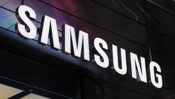 Leuchtende, weiße "SAMSUNG" Buchstaben sind an einer dunklen Fassade montiert.