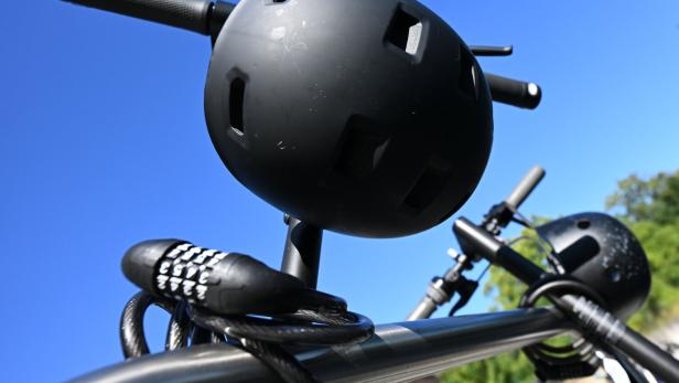 Ein Fahrradschloss und ein schwarzer Fahrradhelm sind vor blauem Himmel zu sehen.