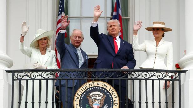 König Charles, Camilla, Donald und Melania Trump winken von einem Balkon mit US-Flagge.