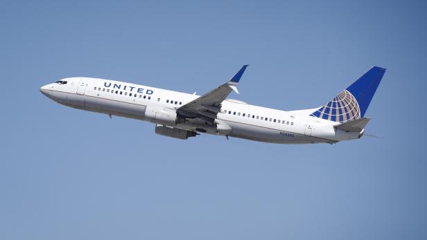 Ein United-Flugzeug mit der Kennung N24202 steigt vor blauem Himmel auf.