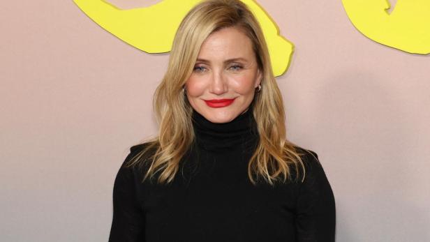 Cameron Diaz trägt ein schwarzes Rollkragenkleid und roten Lippenstift.