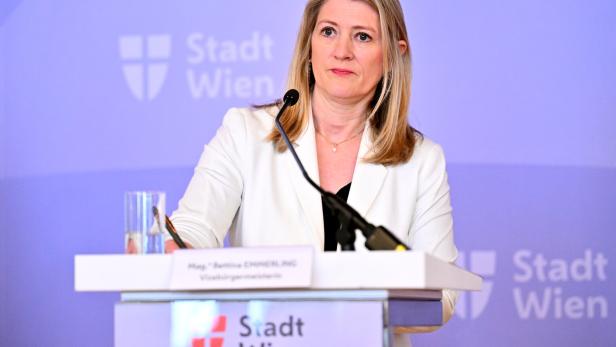 Bettina Emmerling in weißem Blazer steht am Rednerpult mit dem Logo der Stadt Wien.