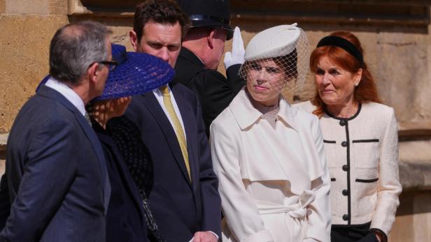 Mehrere Personen, darunter Sarah Ferguson und Prinzessin Eugenie mit Hut und Schleier, stehen beisammen.