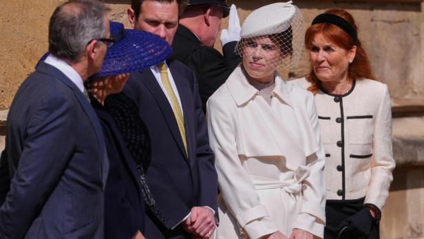 Mehrere Personen, darunter Sarah Ferguson und Prinzessin Eugenie mit Hut und Schleier, stehen beisammen.