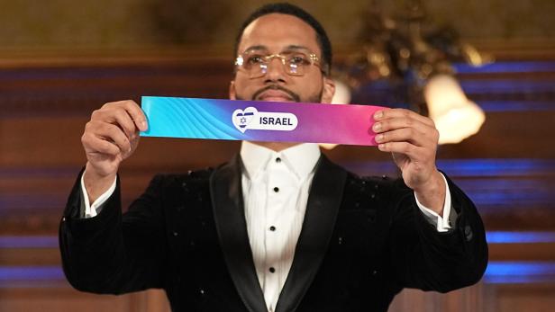 Ein Mann im Anzug hält ein farbiges Schild mit der Aufschrift „Israel“ und einem Herzsymbol mit Davidstern.