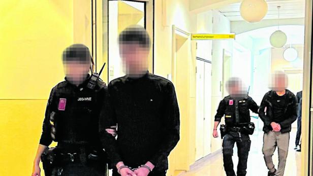 Zwei Angeklagte werden von Justizwachebeamten eskortiert