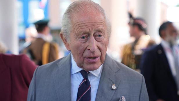König Charles III. im grauen Anzug mit gestreifter Krawatte und Einstecktuch.