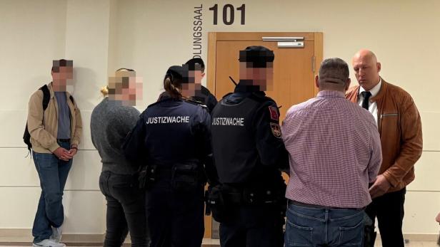 Vor dem Verhandlungssaal 101 stehen Justizwachebeamte mit den Angeklagten und weiteren Personen im Gerichtsgebäude in Wien.