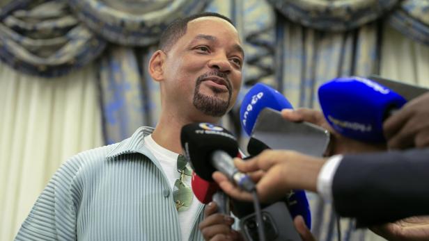 Will Smith wird von Reportern mit Mikrofonen interviewt.