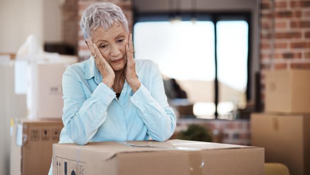 Verzweifelte Seniorin mit Umzugskartons