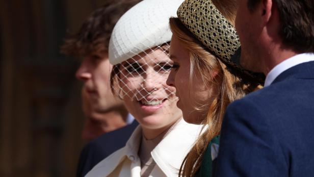 Beatrice und Eugenie mit Hüten unterhalten sich, eine trägt einen weißen Hut mit Schleier.