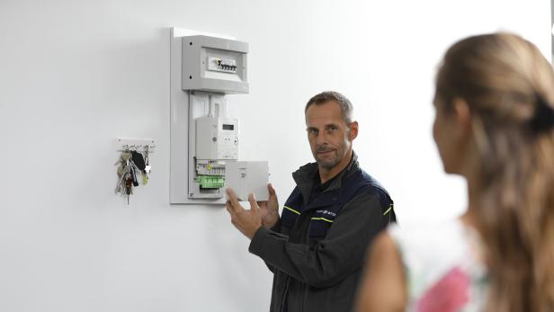 Techniker eines Stromnetzbetreibers zeigt Kundin ihren neuen Smart Meter.