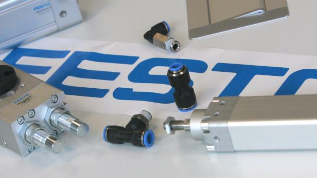Auf einem Tisch liegen Pneumatikzylinder und Verbinder der Firma Festo.