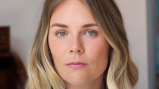 Frau mit schulterlangem, blond-braunem Haar und gestreiftem Hemd blickt ernst in die Kamera.