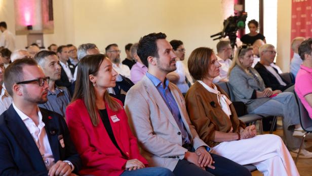 Teilnehmende des Neos NÖ Landesparteitags verfolgen aufmerksam die Präsentation zu Gemeindefusionen und Strukturerneuerungen.