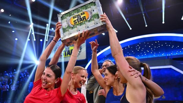 Geldkoffer wird von vier Gewinnerinnen hochgehalten