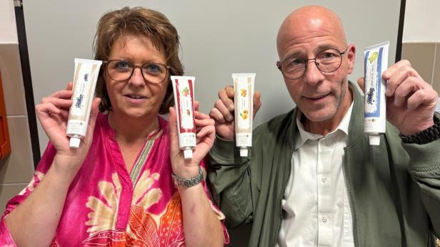 Zwei Personen halten jeweils zwei Tuben mit verschiedenen Fruchtmotiven und lächeln in die Kamera.