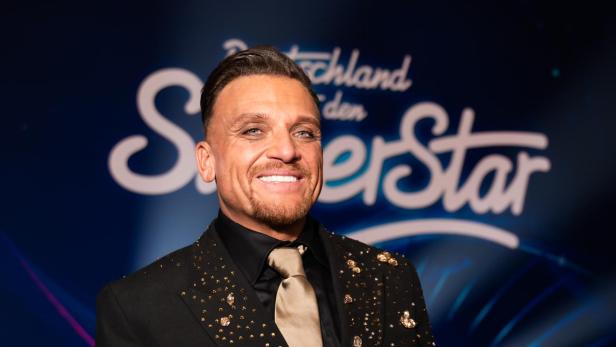 Menowin Fröhlich strahlend im Anzug nach seinem "DSDS"-Sieg auf der Bühne.