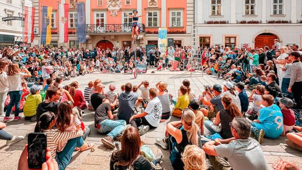 Straßenkünstler tritt vor großem Publikum auf dem Hauptplatz vor dem Rathaus in Wiener Neustadt auf.
