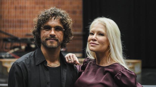 Pete Parkkonen mit lockigen Haaren und Brille steht neben Linda Lampenius mit langen, blonden Haaren und violetter Bluse, beide lächeln leicht.