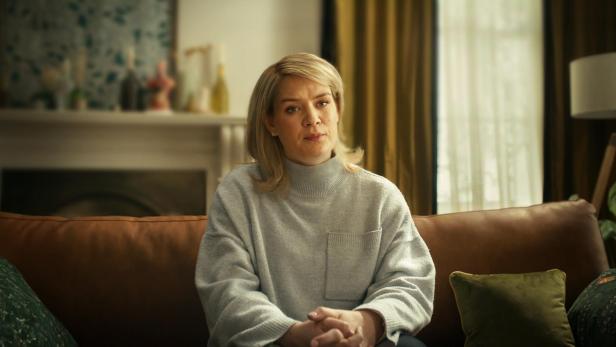 Blonde Frau sitzt auf einem Sofa 