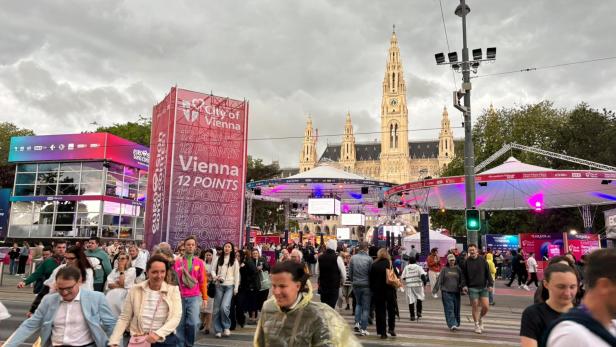 Menschen verlassen geordnet das ESC-Village am Wiener Rathausplatz bei bewölktem Himmel.