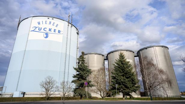 Mehrere Silos von "Wiener Zucker" stehen unter einem bewölkten Himmel.