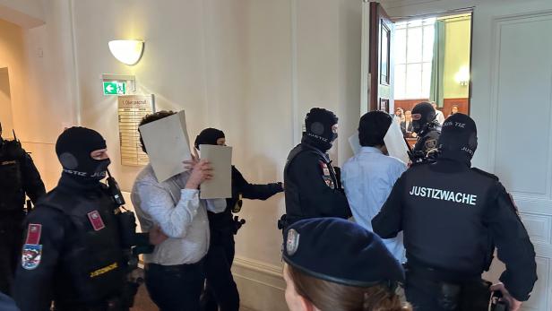 Angeklagte werden in einen Gerichtssaal geführt