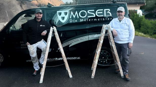 Zwei Handwerker in Arbeitskleidung stehen neben Leitern vor einem Firmenwagen mit der Aufschrift „Moser Die Malermeister“.