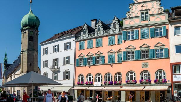 People walking around the rathaus square near chapel of saint george and hilarius in the austrian city bregenz.