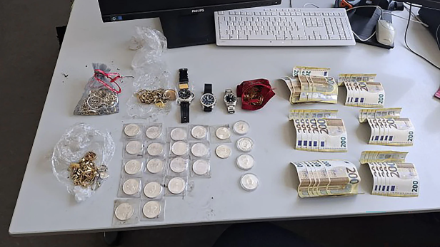 Luxusuhren, Goldschmuck, Silbermünzen und mehrere Bündel 200-Euro-Scheine auf einem Tisch.