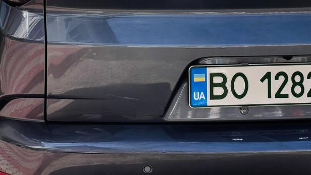 Rear view of a gray Neta U SUV with Ukrainian license plate in a sunny parking lot