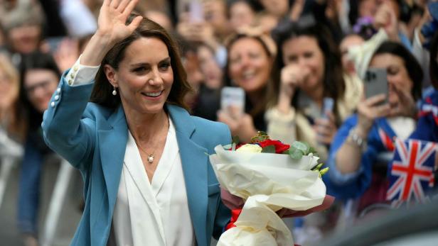 Prinzessin Kate winkt lächelnd in der Menge, einen Blumenstrauß haltend.