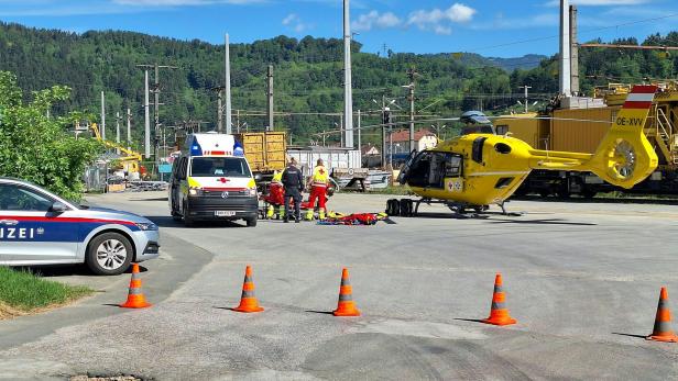 Ein gelber Rettungshubschrauber, ein Rettungswagen und ein Polizeiauto stehen bei einem medizinischen Notfall bereit.
