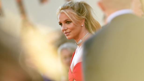 Britney Spears mit hochgesteckten blonden Haaren und rotem Kleid auf einem Event.