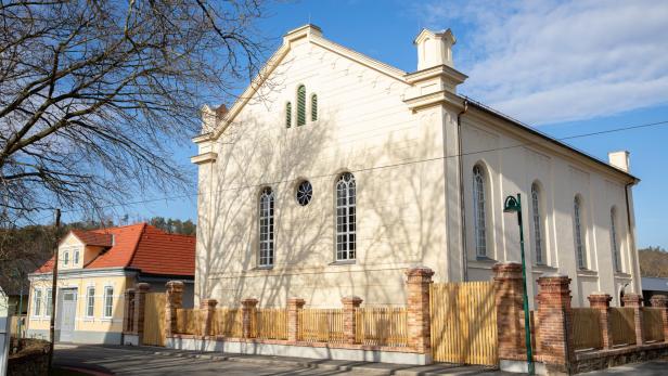 Ehemalige Synagoge Kobersdorf mit hellem Mauerwerk und roten Dachziegeln bei Sonnenschein.