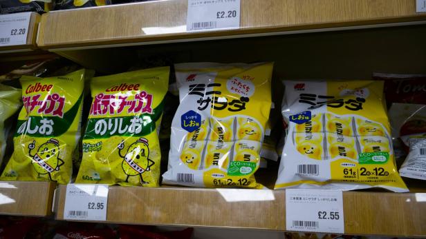 Bunte Calbee-Kartoffelchipstüten mit japanischer Aufschrift im Supermarktregal.