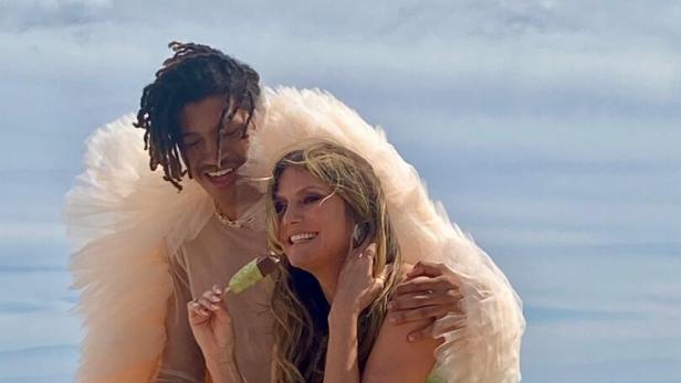 Heidi Klum und ihr Sohn Henry posieren am Strand mit einem Eis und einem Herz aus Lichtern.