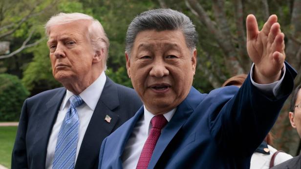 Donald Trump und Xi Jinping sind im Gespräch, wobei Xi die Hand hebt.