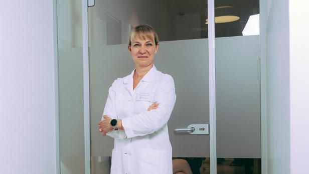 Eine Ärztin in weißem Kittel vor ihrer Praxis