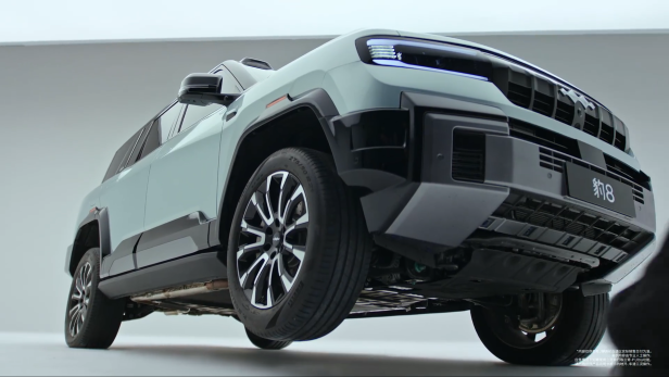 Der Denza B8 SUV von BYD demonstriert den neuen 3-Rad-Modus, bei dem ein Vorderrad deutlich angehoben ist, während die anderen Räder Bodenkontakt haben.