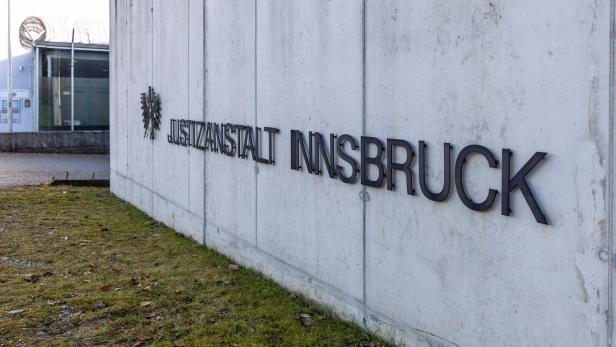 Die Aufschrift "Justizanstalt Innsbruck" ist an einer grauen Betonmauer angebracht.