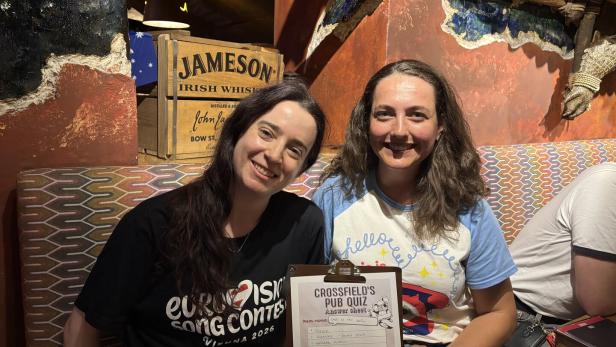 Zwei Frauen lächeln mit einem "Crossfield's Pub Quiz"-Bogen und einem "Eurovision Song Contest"-T-Shirt.