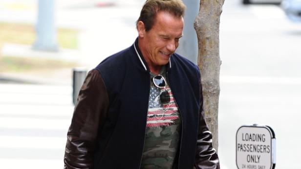 Arnold Schwarzenegger trägt eine Bomberjacke und geht die Straße entlang.