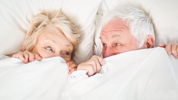 Overhead view of couple hiding in blanket