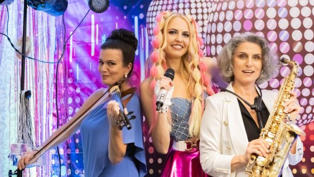 Drei Frauen stehen vor einem bunten Hintergrund