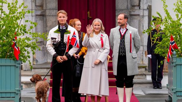 Die norwegische Königsfamilie, darunter Kronprinz Haakon und Kronprinzessin Mette-Marit, steht vor einem Gebäude.