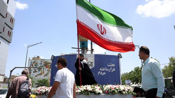 Eine Frau schwenkt die Nationalflagge in Teheran. Das  Regime droht mit Gegenangriffen.   