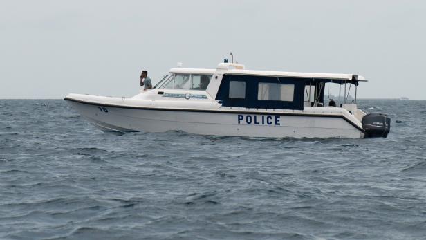 Ein Polizeiboot fährt auf dem Meer, ein Mann steht vorne und blickt in die Ferne.