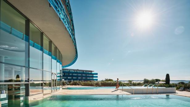 Modernes Hotel mit Poollandschaft, Sonnenschein und Blick aufs Meer in Kroatien.
